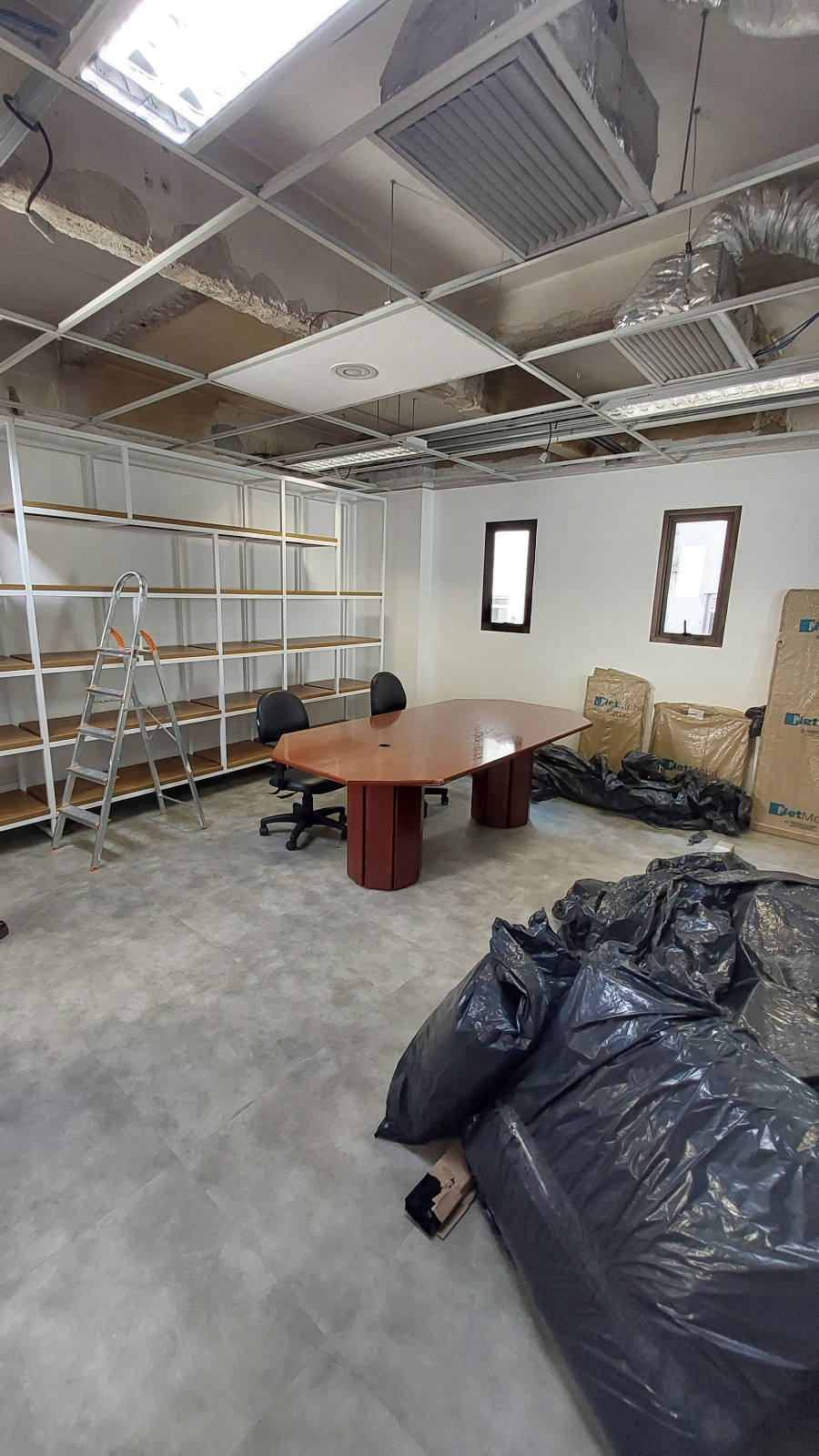 Estúdio em fase de obra com forro, estantes e mesa no local by Yourcast